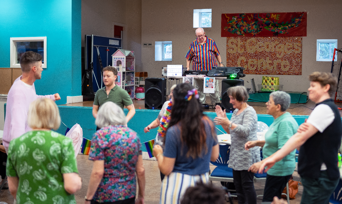 People dancing with a Dj in the back of shot.