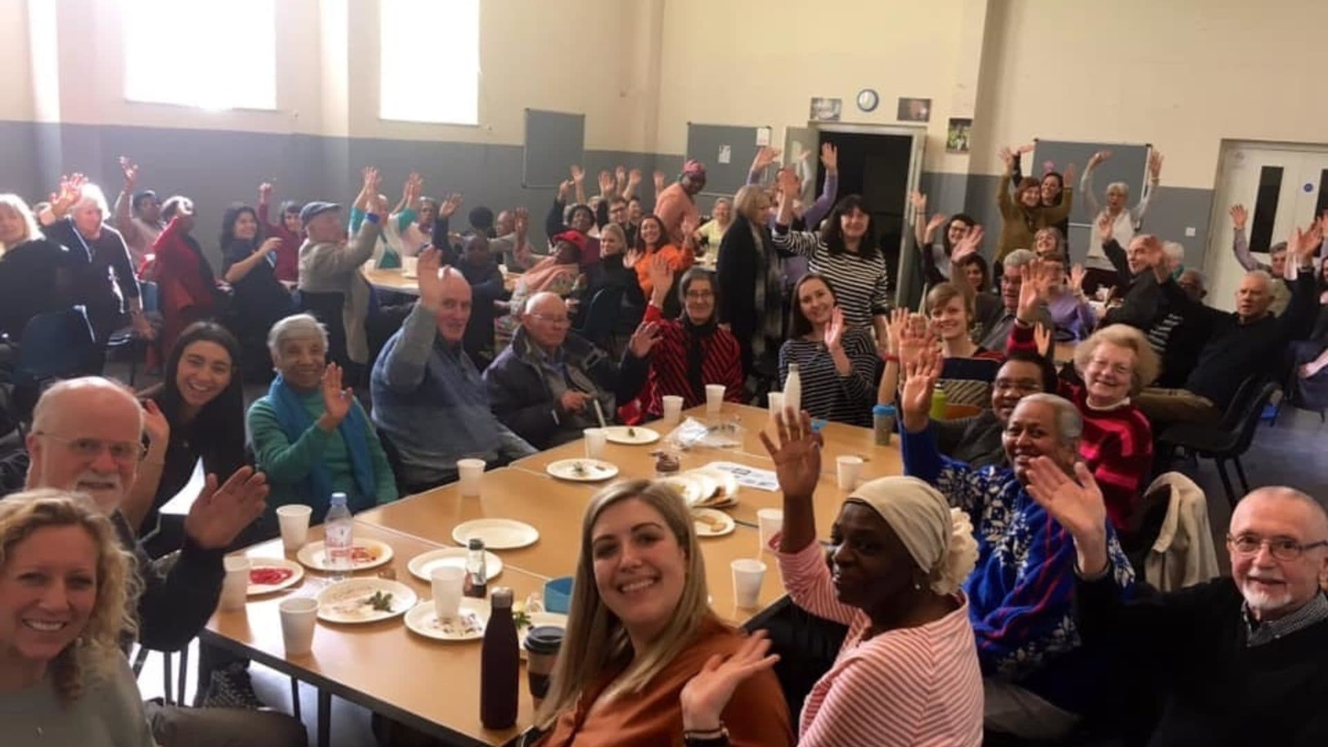 A room of people waving at the camera