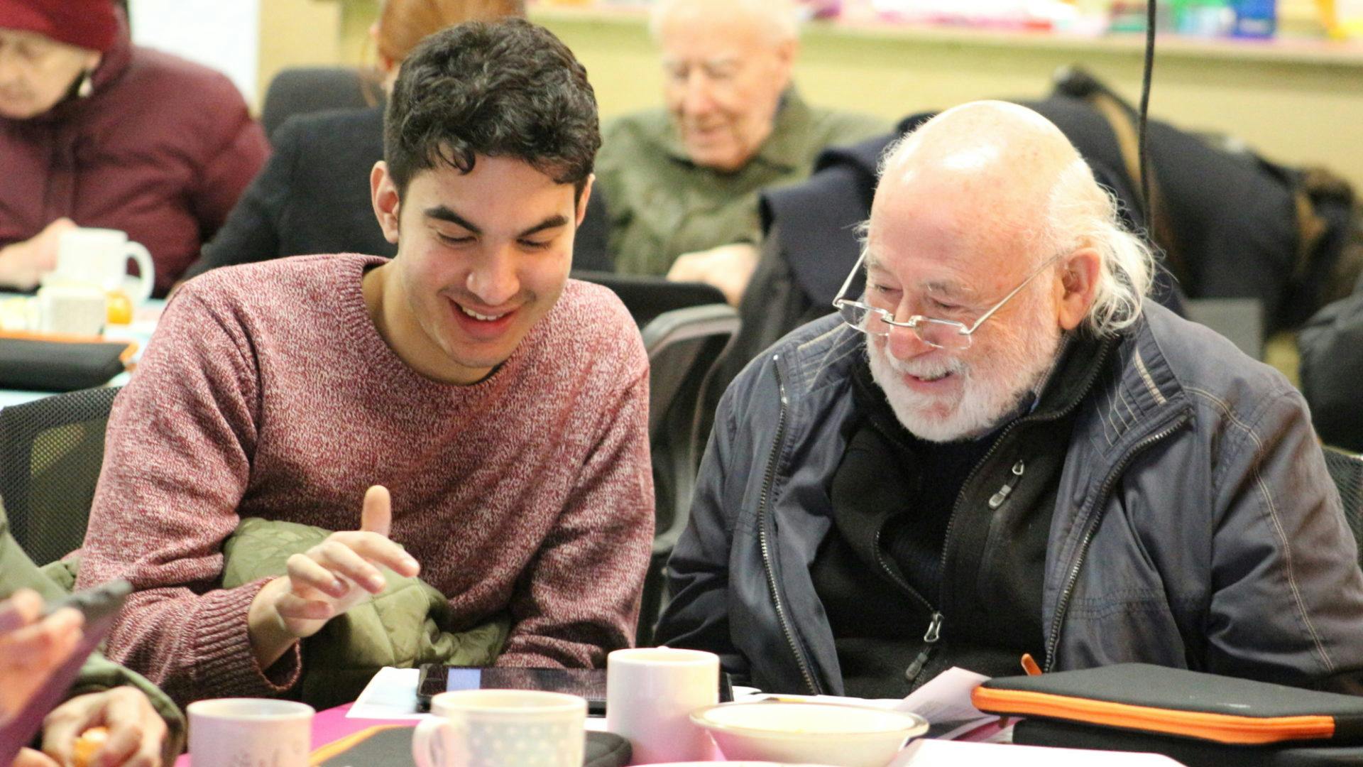 Young man and old man discussing technology