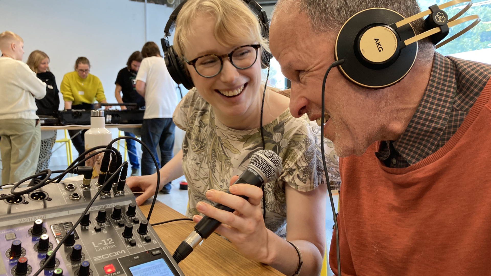 A younger and an older neighbour using recording equipment and laughing